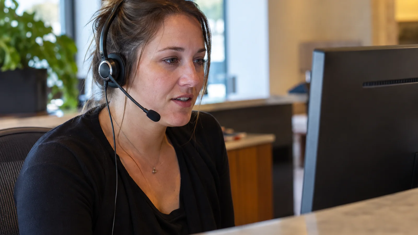 A woman wearing a headset at a reception desk in a law office.